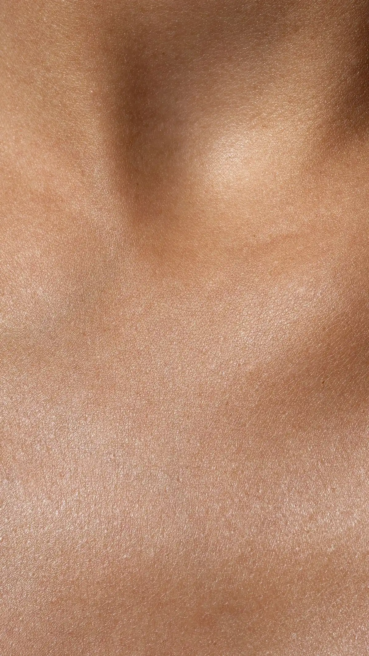 Macro photograph of bare skin on a shoulder and chest, showing natural surface texture and fine lines